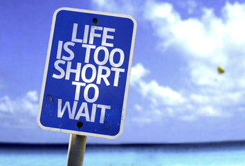 Life is Too Short To Wait sign with a beach on background