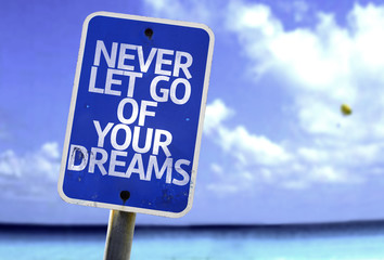 Never Let Go Of Your Dreams sign with a beach