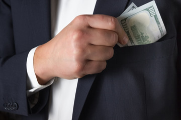 Man hides money dollar into a pocket of his jacket