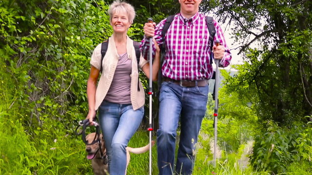 Happy senior couple hiking with dog