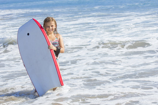 Cute little girl boogie boarding in the ocean
