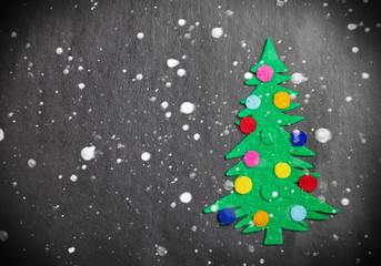 Christmas tree with toys made of felt and falling snowflakes