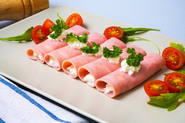 Rolled slices of ham filled with horseradish cream on plate - 72905701