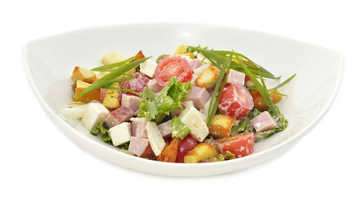 Salad with gammon, cheese and vegetables on white plate