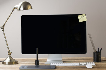 Image of a big computer screen with a lamp and stationary items - obrazy, fototapety, plakaty