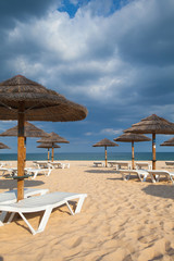 Different parasols and sun loungers on the empty beach on Tavira