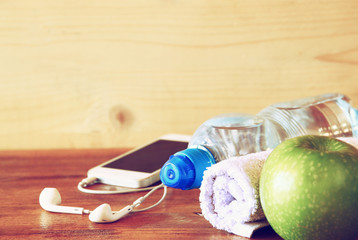 fitness concept with bottle of water, mobile phone with earphone