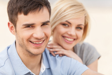 Attractive young couple sitting on beach at summer