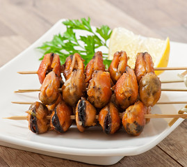 Fried mussels with onions on skewers c garnish of green beans an
