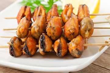 Fried mussels with onions on skewers c garnish of green beans an