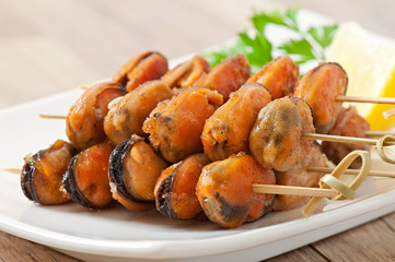 Fried mussels with onions on skewers c garnish of green beans an