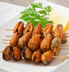 Fried mussels with onions on skewers c garnish of green beans an