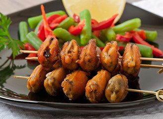 Fried mussels with onions on skewers c garnish of green beans an