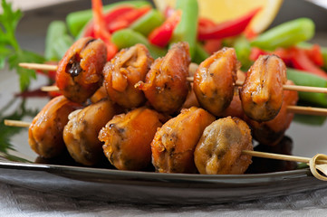 Fried mussels with onions on skewers c garnish of green beans an