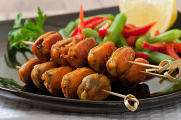 Fried mussels with onions on skewers c garnish of green beans an