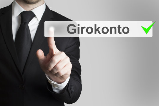 Geschäftsmann in Anzug drückt touchscreen Knopf Girokonto