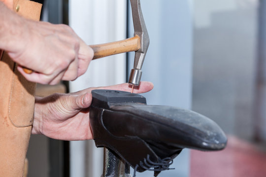 Le cordonnier r&eacute;pare une chaussure