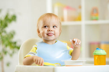smiling baby kid boy eating itself with spoon