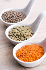 Three kinds of lentil in bowls - red lentil, green lentil and br