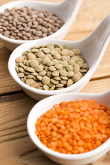 Three kinds of lentil in bowls - red lentil, green lentil and br