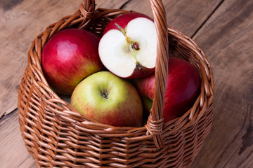 Fresh red apples in basket over wooden background