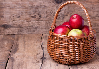 Obraz na płótnie Canvas Fresh red apples in basket over wooden background
