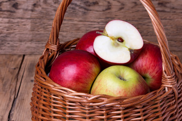 Fresh red apples in basket over wooden background