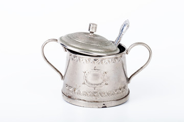 old sugar bowl with lid and spoon with spots of rust on a white