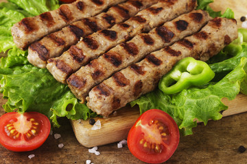 Veal Kebapche with vegetables and bread on wooden board