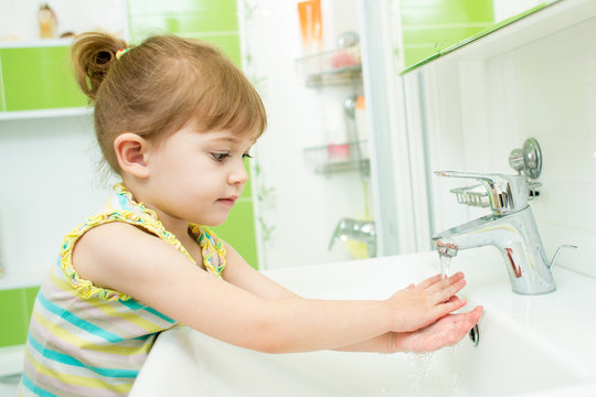 Cute little girl washing her hands in bathroom