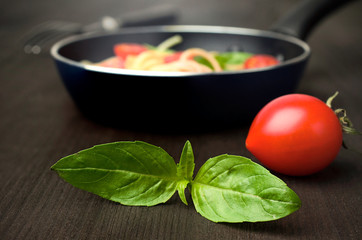 tomato with fresh basil and a frying pan