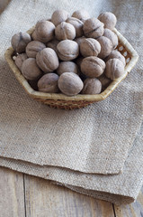 Walnuts in a wicker basket on a piece of burlap.