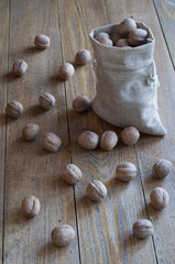 Walnuts in a canvas sack on wooden table.
