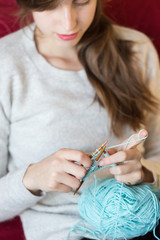 Young woman knitting at home