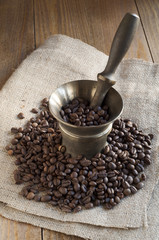 Coffee beans scattered on burlap around the mortar.