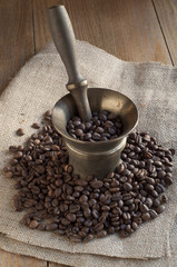 Coffee beans on sackcloth and bronze mortar.