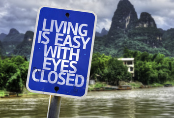 Living is Easy With Eyes Closed sign with a beach