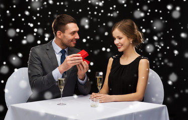 smiling couple with red gift box at restaurant