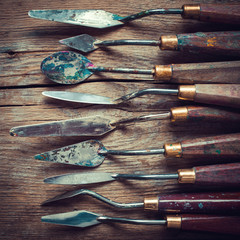 row of artist palette knifes on old wooden table