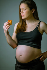 Pregnant women showing her belly and ready to eat cake