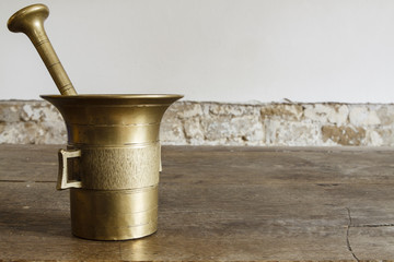 Old bronze mortar with pestle on wootden table