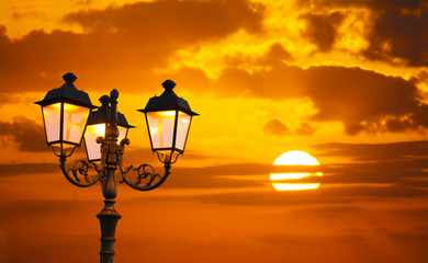 Obraz premium orange sky with a shining sun and a lamppost