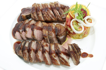 goose breast with vegetables on a white plate