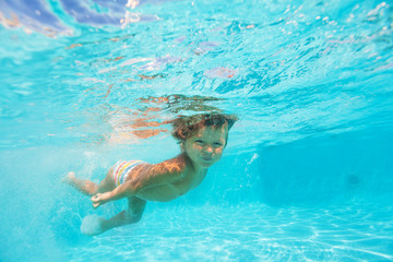 Looking boy moving while swimming undewater
