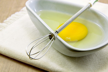 Egg in bowl with whisk on cloth close up