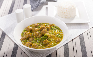 Large bowl of curried sausages with peas and a side of rice as gluten free meal