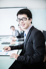 Businessman smiling at the camera while his team is working in t
