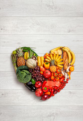 Heart symbol. Healthy eating concept / food photography of heart made from different fruits and vegetables on white wooden table