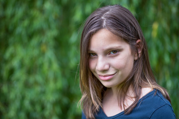 Fototapeta premium Portrait of girl in front of green willow
