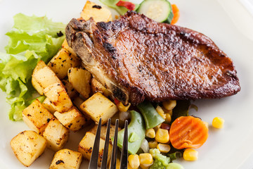 Fried pork with potatoes and vegetables salad